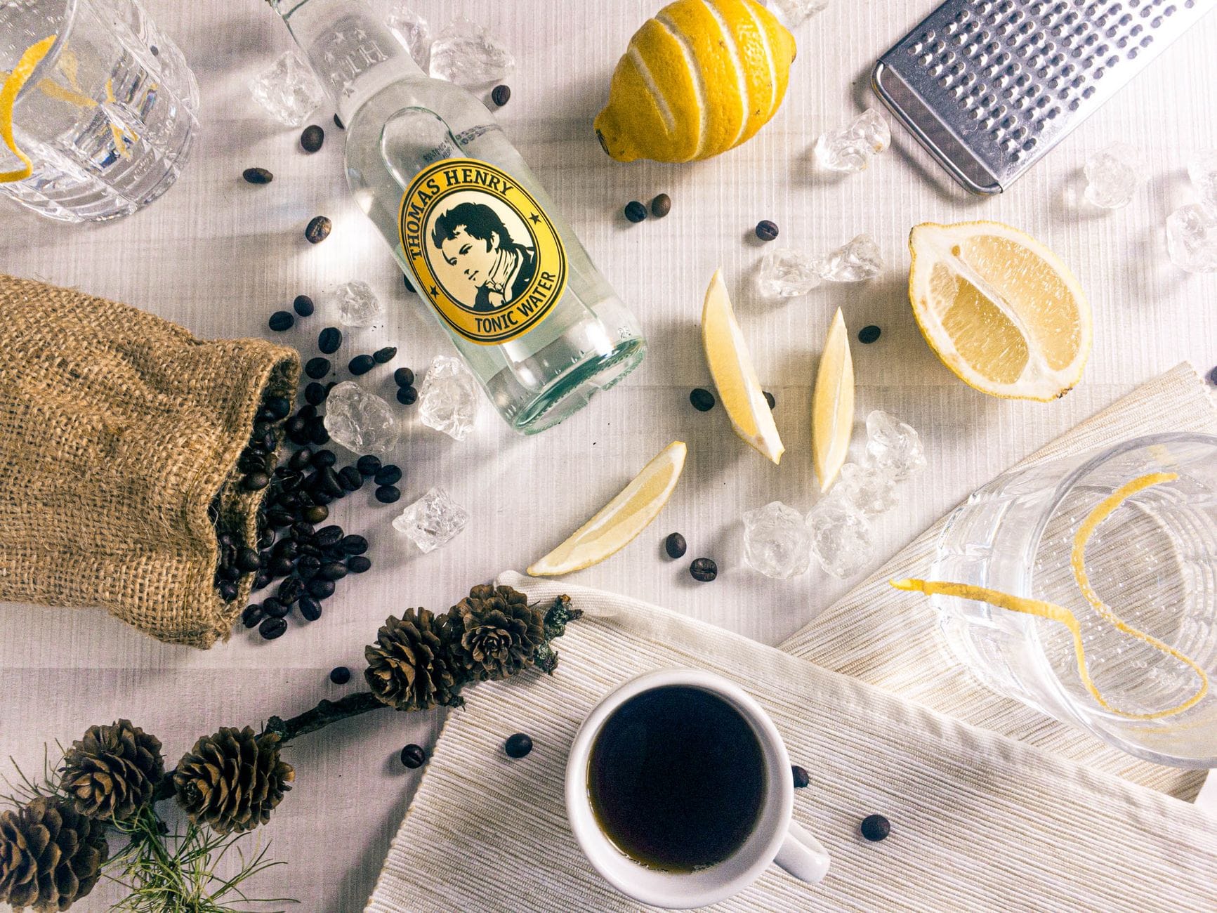 Flat lay: filiżanka kawy, cytryna i butelka toniku na stole