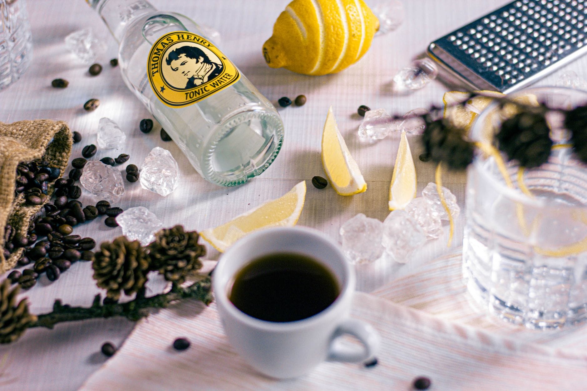 Domowy tonic espresso – prosty przepis na orzeźwiający kawowy drink bez alkoholu Składniki na domowy tonic espresso: kawa, tonik i cytrusy na stole