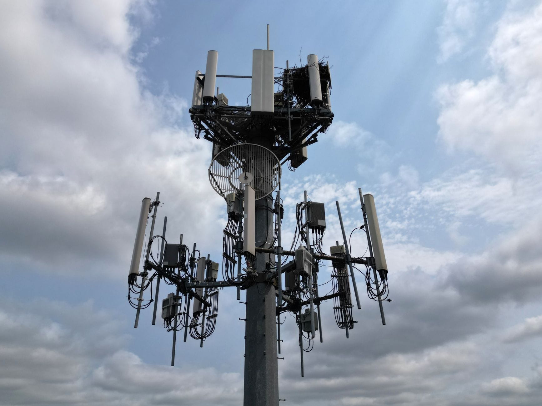 Energochłonność 5G: ile naprawdę kosztuje nas szybka łączność i jak ją optymalizować Nowoczesna wieża telekomunikacyjna z antenami pod pochmurnym niebem